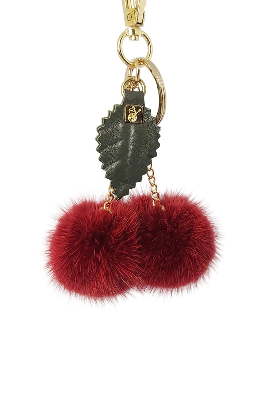Keychain with red fur pom-poms and gold accents on a white background