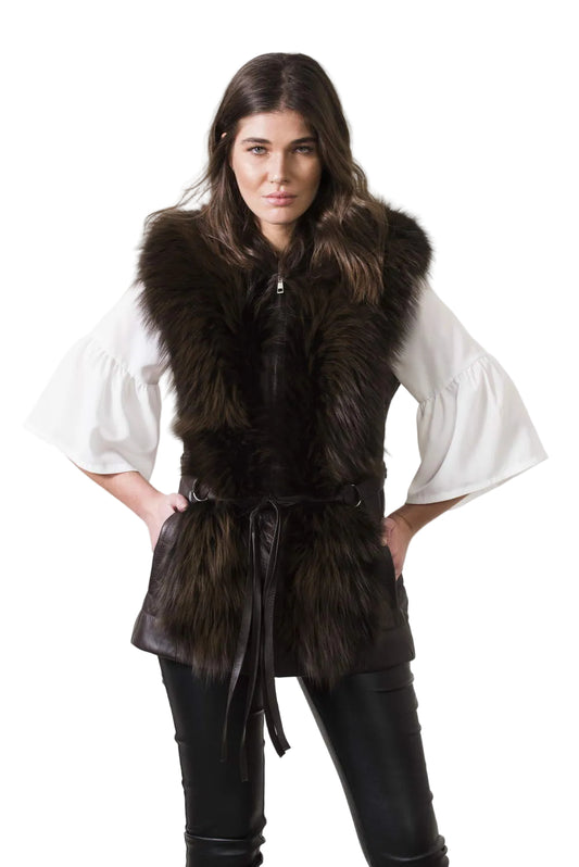 Woman wearing a dark fur vest over a white shirt on a plain background