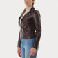 Woman wearing a bURGUNDY leather jacket and blue jeans on a white background