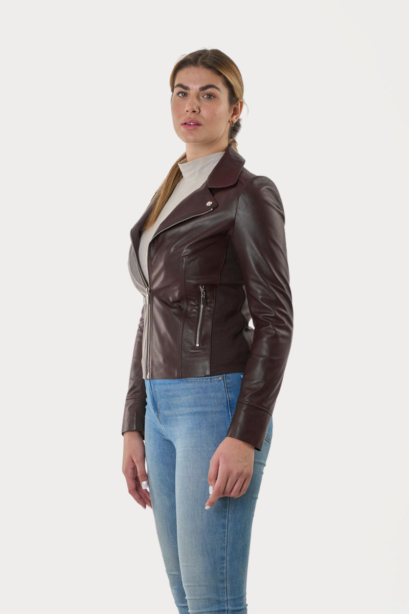 Woman wearing a bURGUNDY leather jacket and blue jeans on a white background