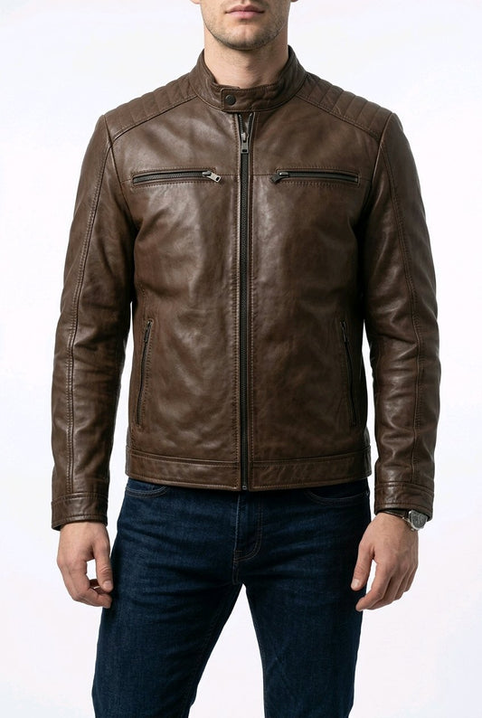A man wearing a brown leather jacket with a stand collar, zippered chest pockets, and zippered side pockets, paired with dark blue jeans against a white studio background.