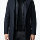 Man wearing a dark blue coat over a black shirt and pants on a white background