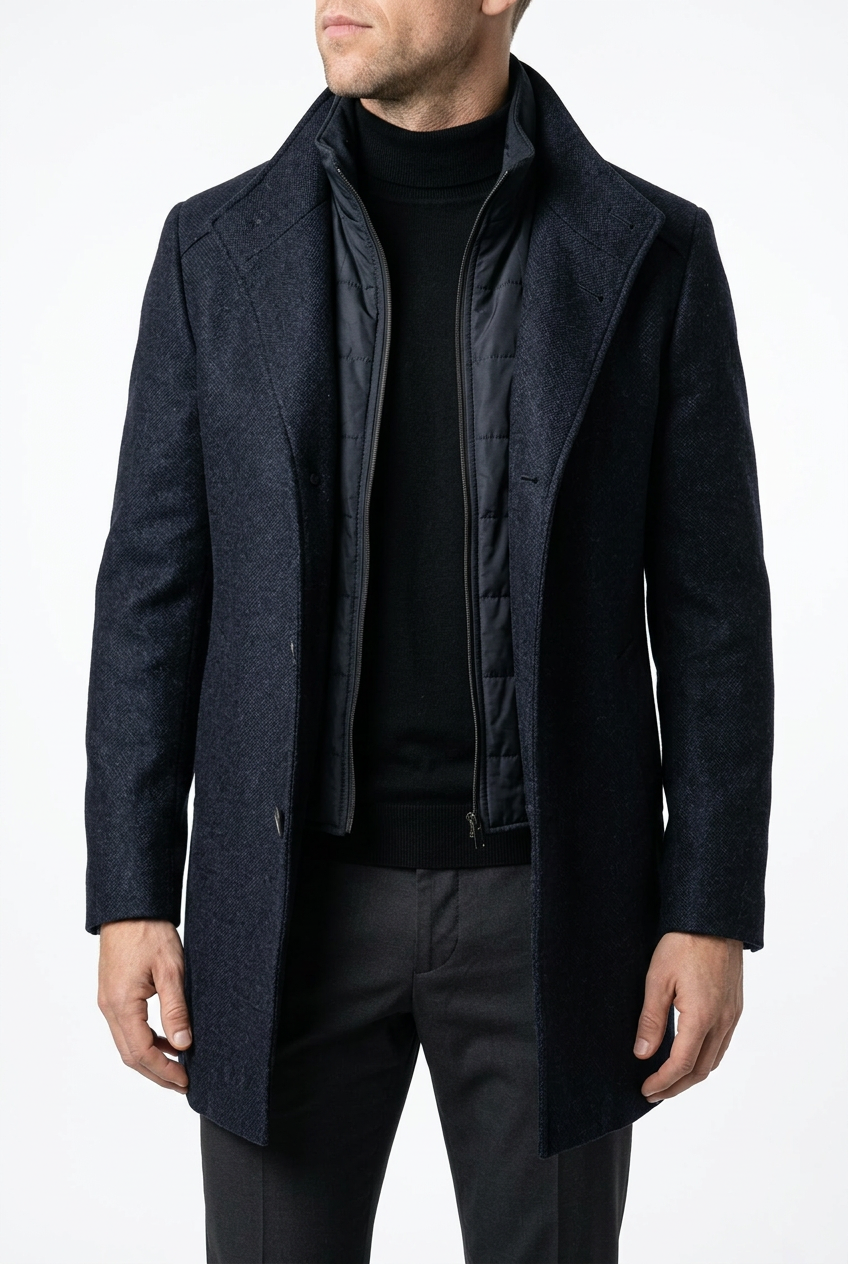 Man wearing a dark blue coat over a black shirt and pants on a white background