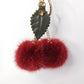 Keychain with red fur pom-poms and gold accents on a white background