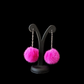Pink fuzzy earrings on a black stand against a black background